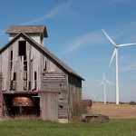 Old Midwestern barn with modern wind turbines behind it