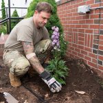 Volunteer planting flowers in a new community garden bed